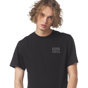Person wearing a black t-shirt with 'Academy Museum Los Angeles' text on a white background